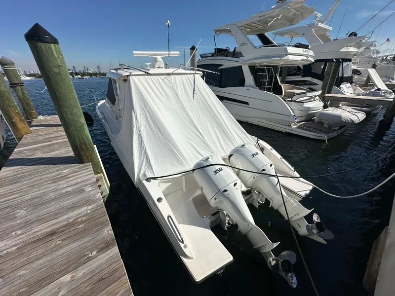 Slide: The Image of 2017 Pursuit OS 355 Offshore boat docked with protective cover and twin outboard motors. - 3