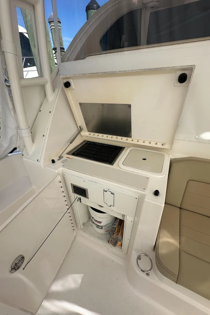 Slide: The Image of 2017 Pursuit OS 355 Offshore boat interior with kitchenette and seating area. - 30