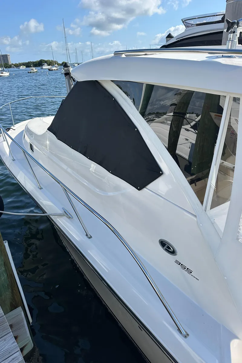 Slide: The Image of 2017 Pursuit OS 355 Offshore boat docked by the water on a sunny day. - 40