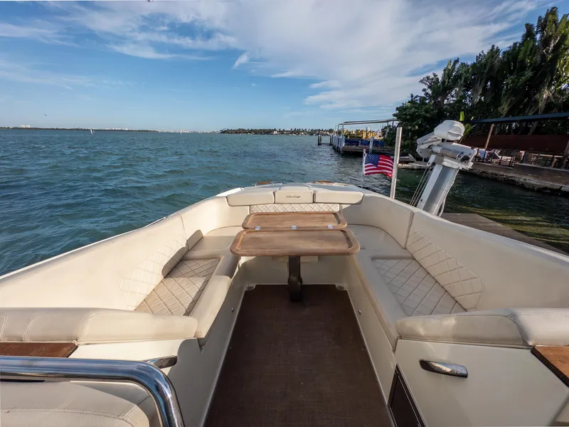 Slide: The Image of 2014 Chris-Craft Launch 32 boat with elegant seating and wooden table on a scenic waterfront. - 30