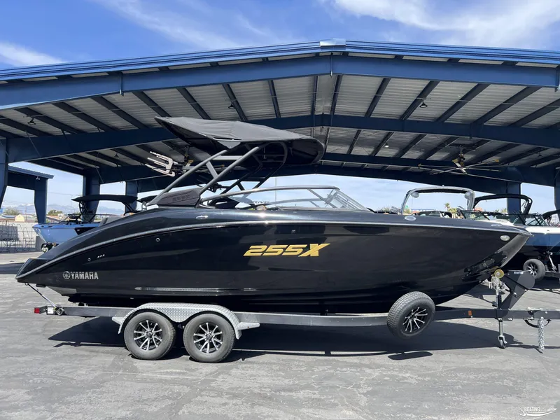 Slide: The Image of 2025 Yamaha Boats 255XD, sleek black design, parked under a metal canopy. - 0