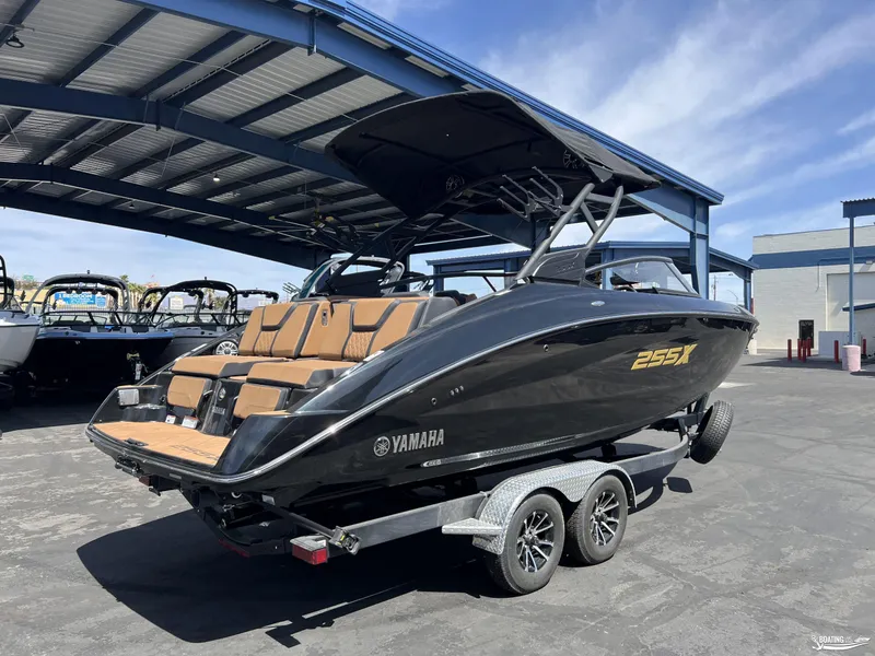 Slide: The Image of 2025 Yamaha Boats 255XD in black, parked on a trailer under a metal canopy. - 1