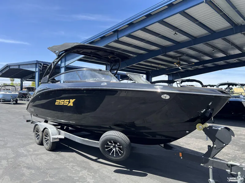 Slide: The Image of 2025 Yamaha Boats 255XD in black, parked under a metal canopy. - 2