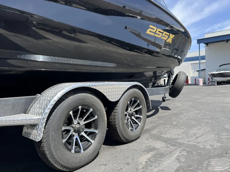 Slide: The Image of 2025 Yamaha Boats 255XD on trailer, showcasing sleek black design and dual axle wheels. - 3