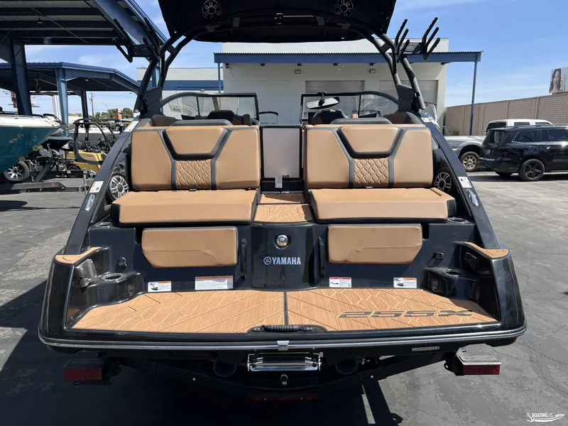 Slide: The Image of 2025 Yamaha Boats 255XD with tan seating and sleek design, parked outdoors. - 4
