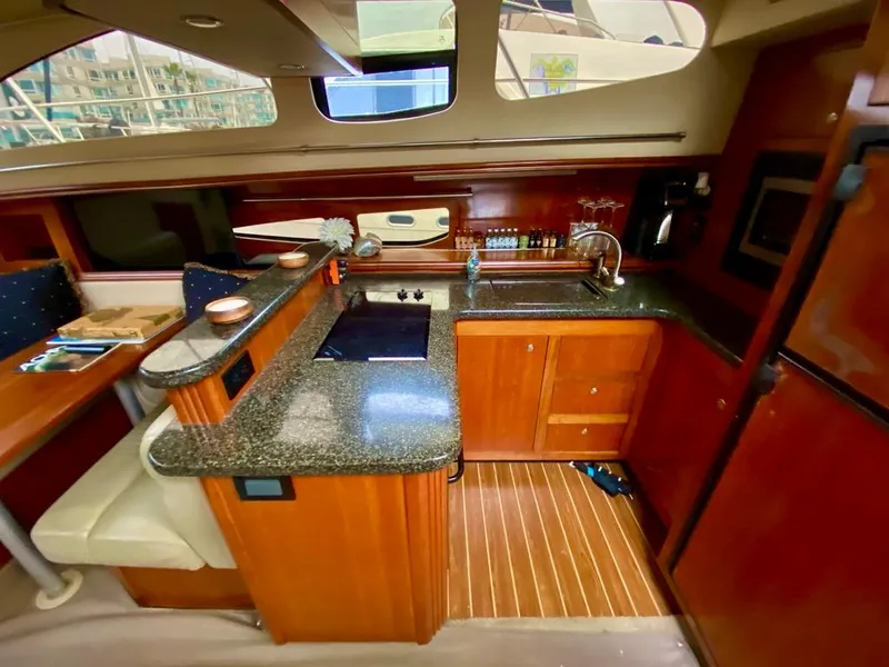 Slide: The Image of Luxurious 2005 Cruisers Yachts 405 Express Motoryacht interior kitchen with wood cabinetry and granite countertops. - 15