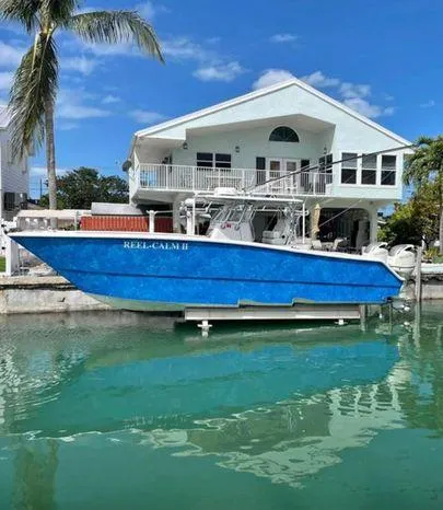 Slide: The Image of 2020 Freeman 34VH boat docked by waterfront house, clear blue sky, and palm tree. - 1