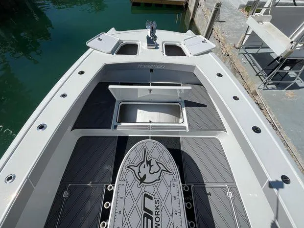 Slide: The Image of 2020 Freeman 34VH boat deck with storage compartments and logo, docked by the water. - 22