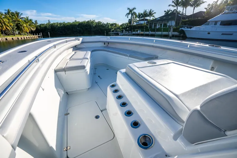 Slide: The Image of 2021 Yellowfin 42 boat interior with seating and rod holders, docked near palm trees. - 23