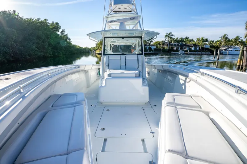 Slide: The Image of 2021 Yellowfin 42 boat with spacious deck and seating, docked by lush greenery. - 24