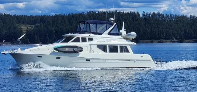 Slide: The Image of 2000 McKinna 57 Pilothouse yacht cruising on a serene lake with forested shoreline. - 26