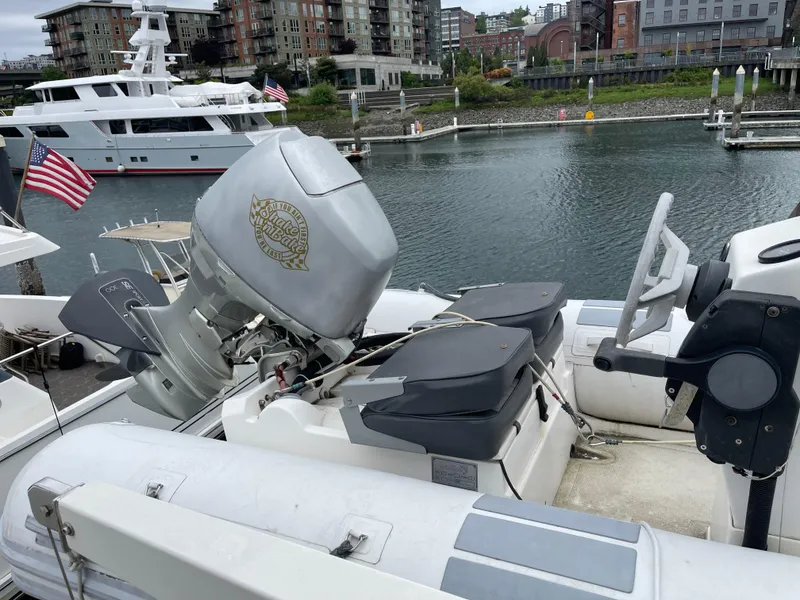 Slide: The Image of 2000 McKinna 57 Pilothouse yacht docked in marina, featuring outboard motor and American flag. - 43