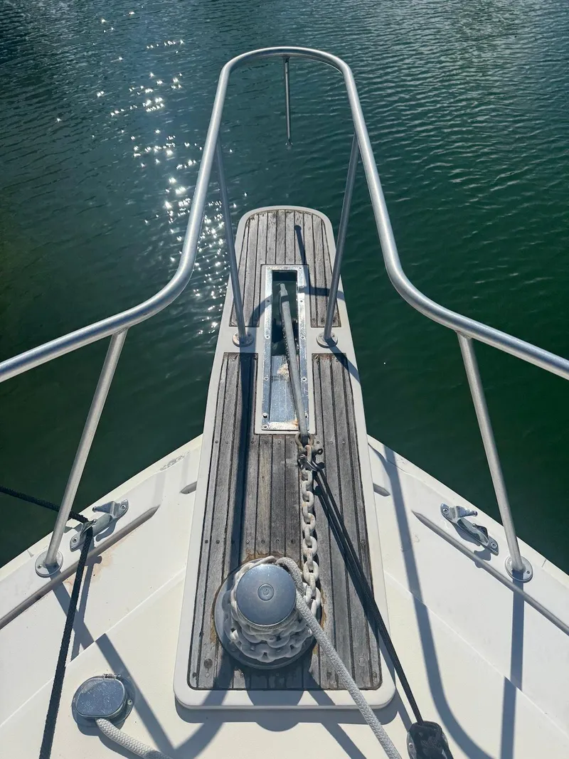 Slide: The Image of 1989 Bertram 50 Convertible boat bow with anchor and railing on calm water. - 11