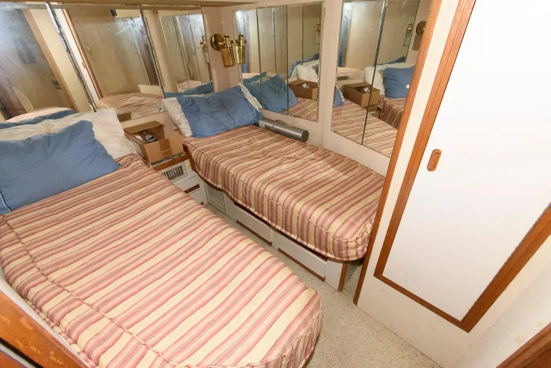 Slide: The Image of 1989 Bertram 50 Convertible cabin with twin beds, striped bedding, and mirrored walls. - 21