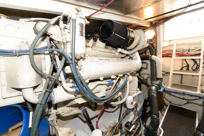 Slide: The Image of Engine room of a 1989 Bertram 50 Convertible yacht, showcasing complex machinery and piping. - 28