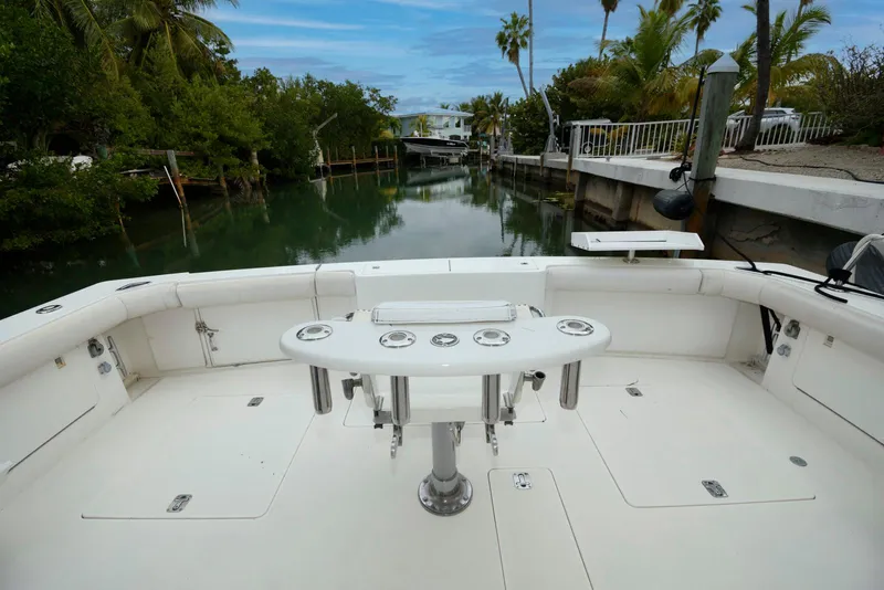 Slide: The Image of 1989 Bertram 50 Convertible boat deck with fishing rod holders, docked in a serene canal setting. - 4