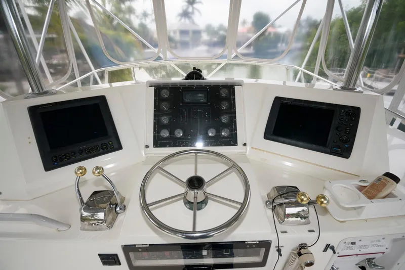 Slide: The Image of Control panel of a 1989 Bertram 50 Convertible yacht with steering wheel and navigation screens. - 9