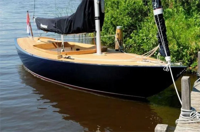 Slide: The Image of 2025 Rustler 24 sailboat docked on calm water, featuring sleek design and wooden deck. - 14