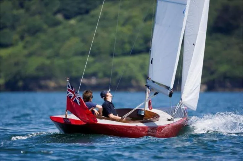 Slide: The Image of Sailing on a Rustler 24 boat, 2025 model, with vibrant red hull and white sails. - 2