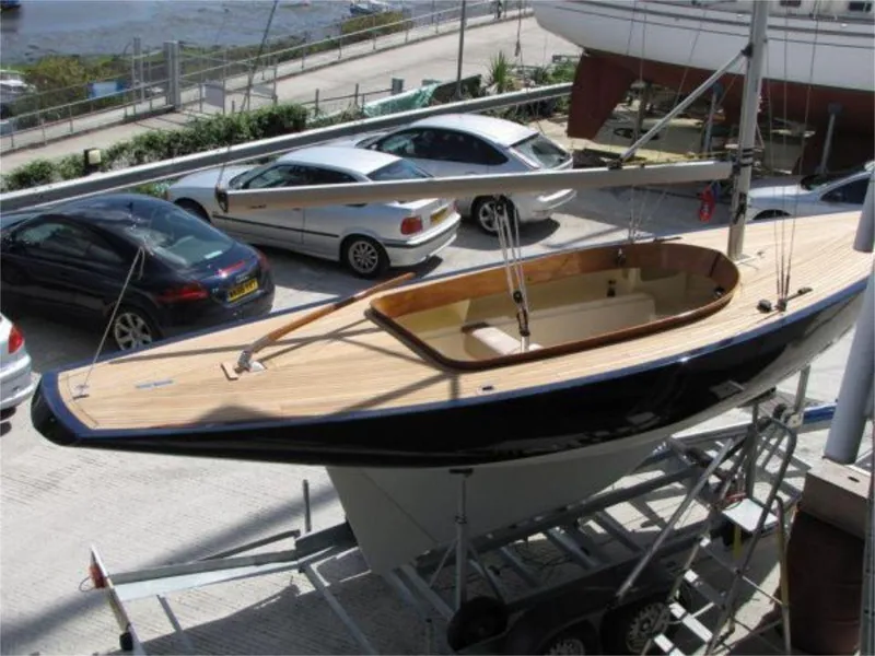 Slide: The Image of 2025 Rustler 24 sailboat on trailer, parked near cars, showcasing sleek design and wooden deck. - 22