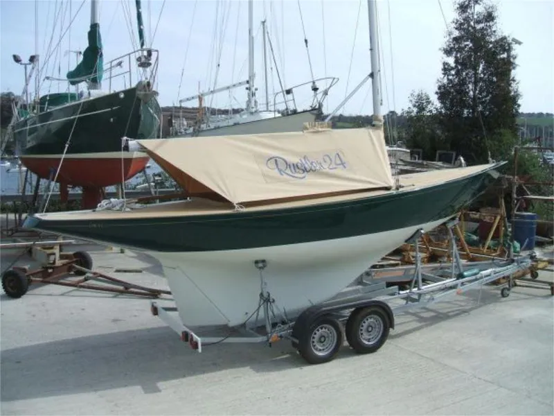Slide: The Image of 2025 Rustler 24 sailboat on trailer, docked in a marina setting. - 24