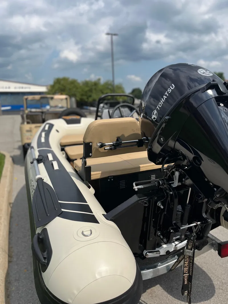 Slide: The Image of 2025 Highfield Classic 360 GT boat with Tohatsu outboard motor, parked outdoors. - 6