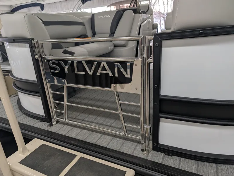 Slide: The Image of 2025 Sylvan L3 DLZ Bar pontoon boat interior with sleek seating and branded gate. - 2