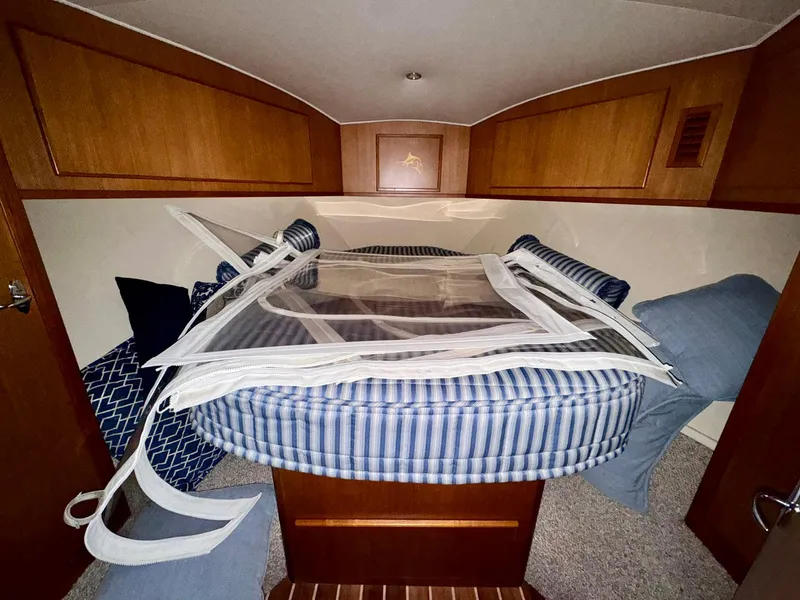 Slide: The Image of 2011 Henriques 42 Sportfisherman cabin with striped bedding and wooden cabinetry. - 11