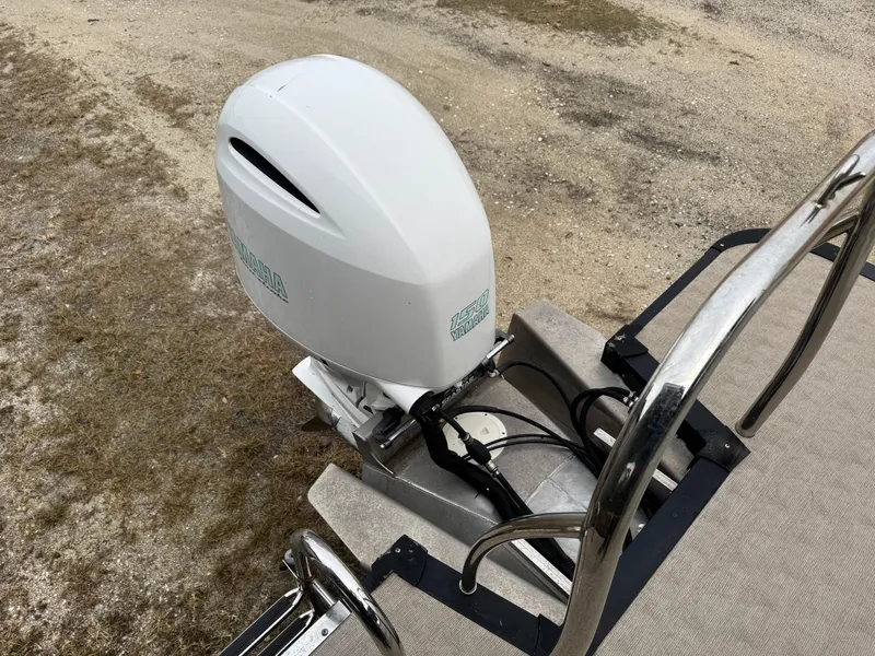 Slide: The Image of 2017 Avalon Catalina Rear J Lounger boat with outboard motor on sandy terrain. - 14