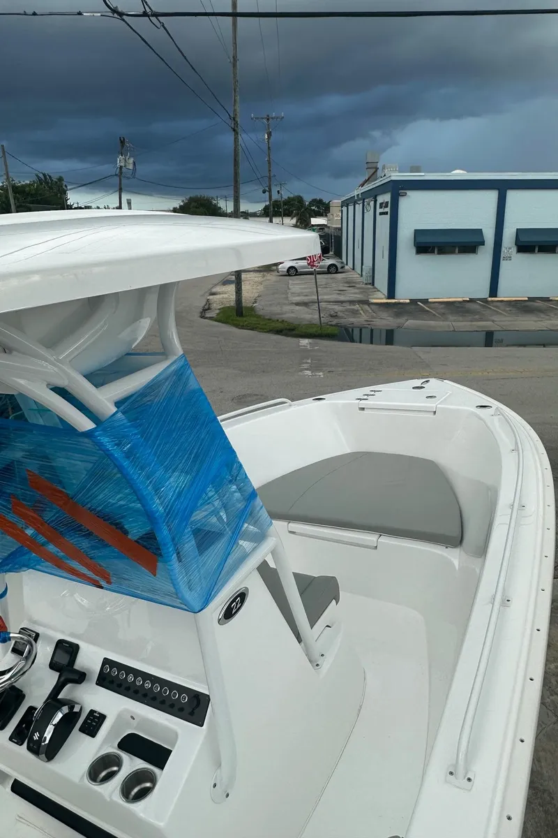 Slide: The Image of 2024 Cape Horn 22OS boat with T-top, docked near industrial buildings under cloudy skies. - 5