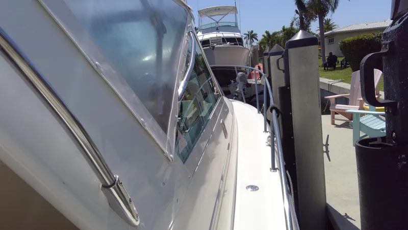 Slide: The Image of 1993 Tiara Yachts 3100 Open docked, side view with clear skies and palm trees. - 19