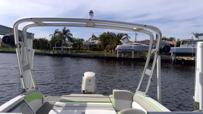 Slide: The Image of 2017 Starcraft SCX 240 boat on water, docked near palm trees and waterfront homes. - 25