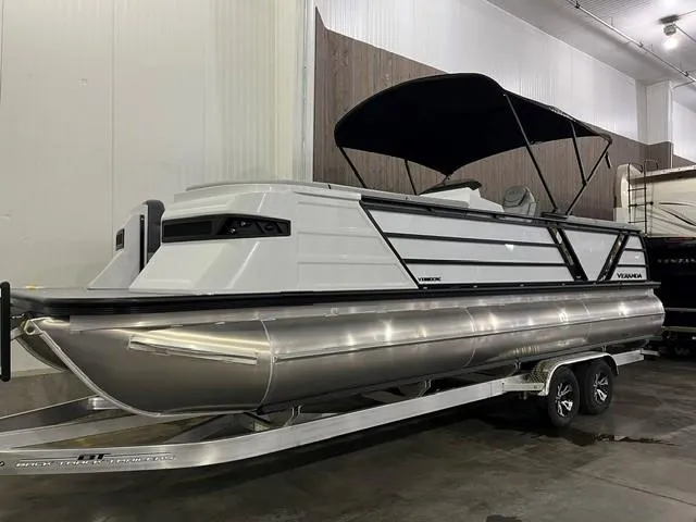 The Image of 2025 Veranda VX 25 DCRC pontoon boat with black canopy on trailer in indoor storage. - 9