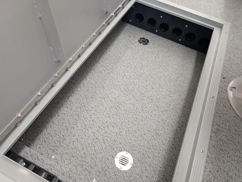 Slide: The Image of 2023 Starcraft Stealth 16 SC storage compartment with gray carpeted interior and drainage holes. - 6