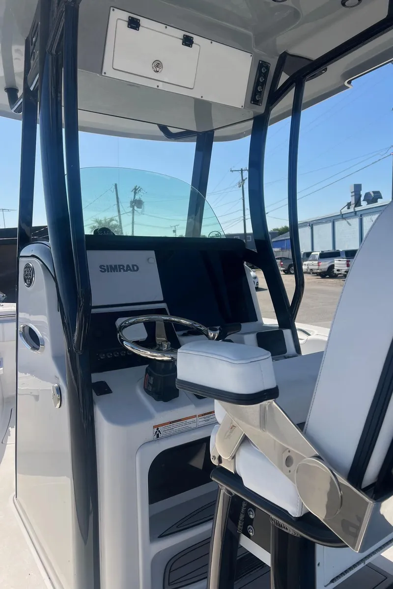 Slide: The Image of 2024 Sea Pro 242 DLX boat console with steering wheel and Simrad display. - 2