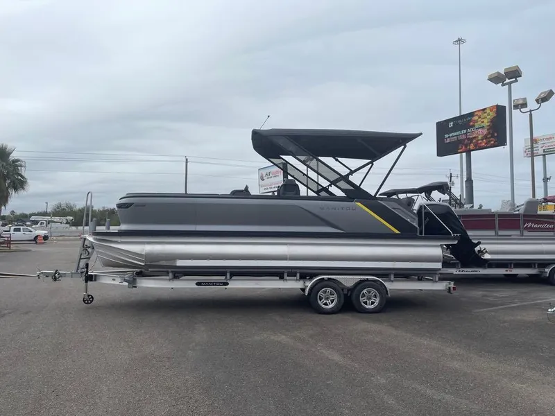 Slide: The Image of 2024 Manitou Explorer 24 pontoon boat on trailer, parked outdoors. - 1