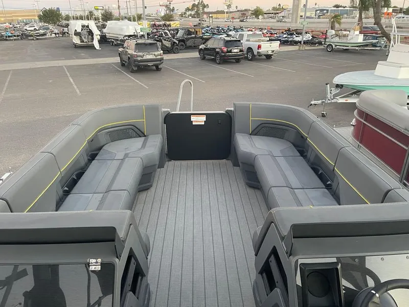 Slide: The Image of 2024 Manitou Explorer 24 pontoon boat with spacious seating in a parking lot. - 13