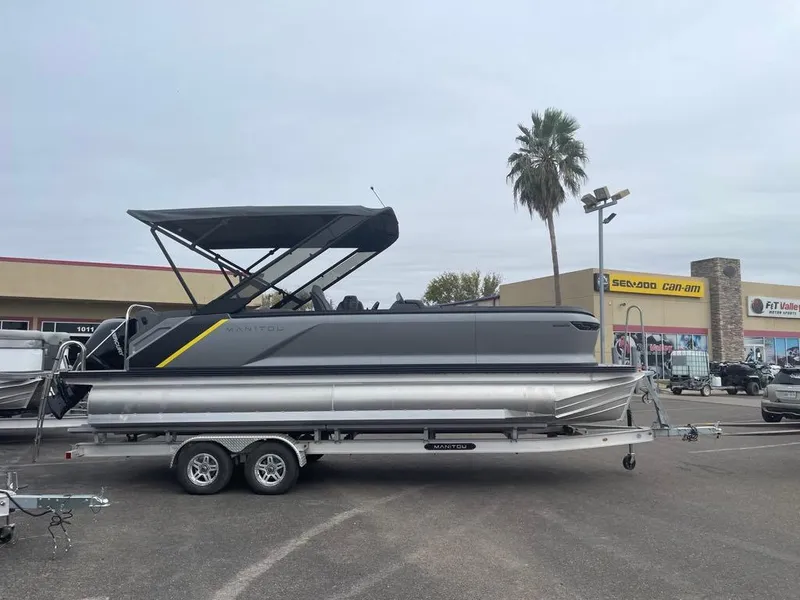 Slide: The Image of 2024 Manitou Explorer 24 pontoon boat on trailer in parking lot. - 2