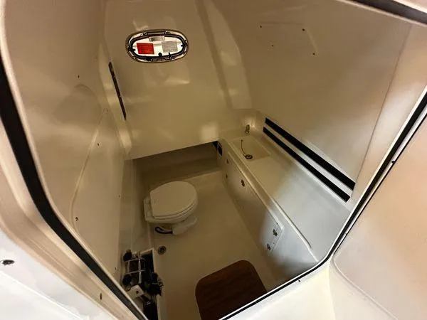 Slide: The Image of Interior cabin of 2022 Boston Whaler 330 Outrage, featuring a compact marine toilet. - 14