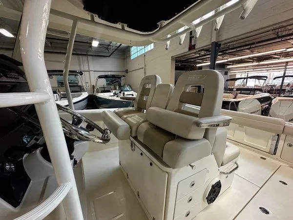 Slide: The Image of 2022 Boston Whaler 330 Outrage interior with dual helm seats in a showroom. - 17
