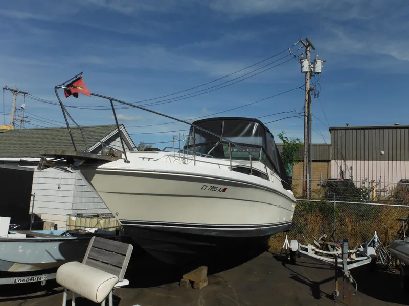 The Image of 1988 Sea Ray 270 Sundancer boat on dry dock, with canopy and flag. - 1