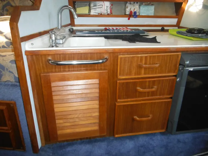 Slide: The Image of 1988 Sea Ray 270 Sundancer kitchen with wooden cabinets and sink. - 17