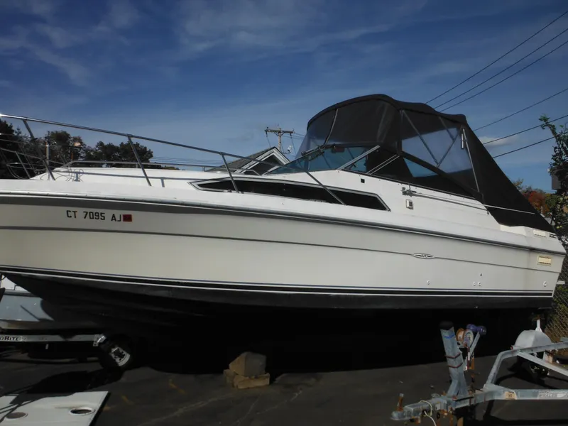 Slide: The Image of 1988 Sea Ray 270 Sundancer boat with black canopy, docked on land. - 4