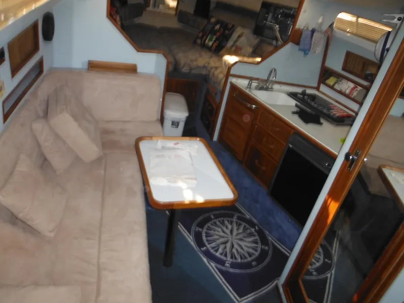 Slide: The Image of Interior of 1988 Sea Ray 270 Sundancer with cozy seating, kitchenette, and nautical decor. - 7