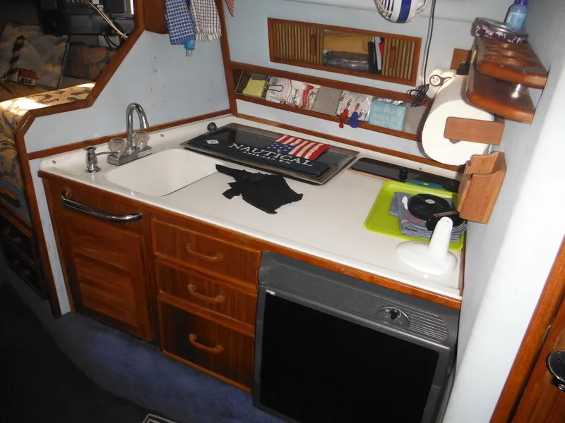 Slide: The Image of 1988 Sea Ray 270 Sundancer kitchen with sink, wooden cabinets, and compact appliances. - 9