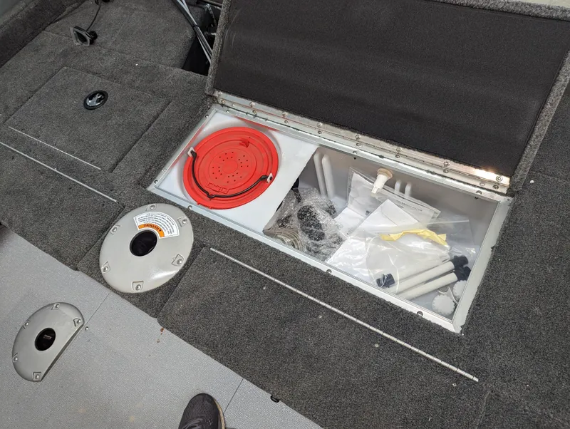 Slide: The Image of 2023 Starcraft Storm 166 DC Pro boat storage compartment with accessories and red lid. - 7
