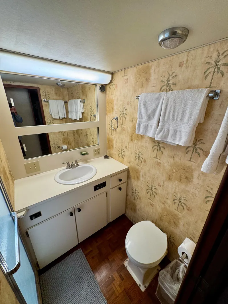 Slide: The Image of 1984 Hatteras Motor Yacht bathroom with palm tree wallpaper, vanity, and towels. - 22