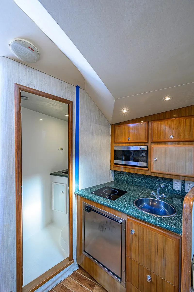 Slide: The Image of 2008 Jersey Cape Devil 36 yacht interior with kitchenette, featuring wood cabinets and modern appliances. - 35