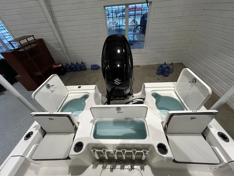 Slide: The Image of 2025 Sea Pro 210 Bay boat with open storage compartments and outboard motor in a garage. - 14