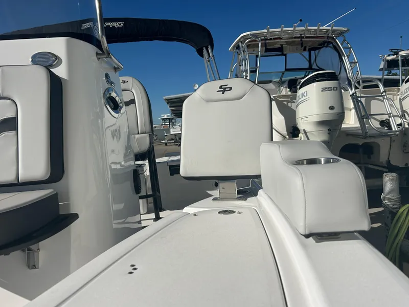 Slide: The Image of 2025 Sea Pro 210 Bay boat interior with seating and console, docked alongside other boats. - 21